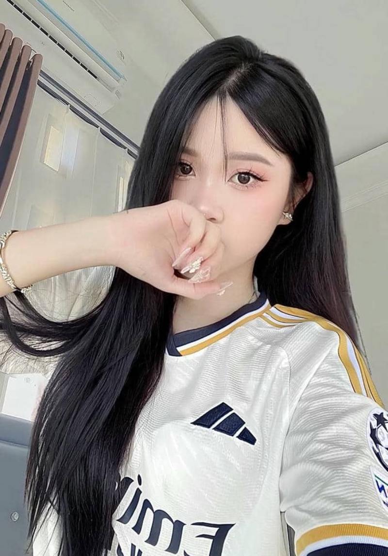 Gái xinh che mặt bằng tay phải, mặc áo bóng đá