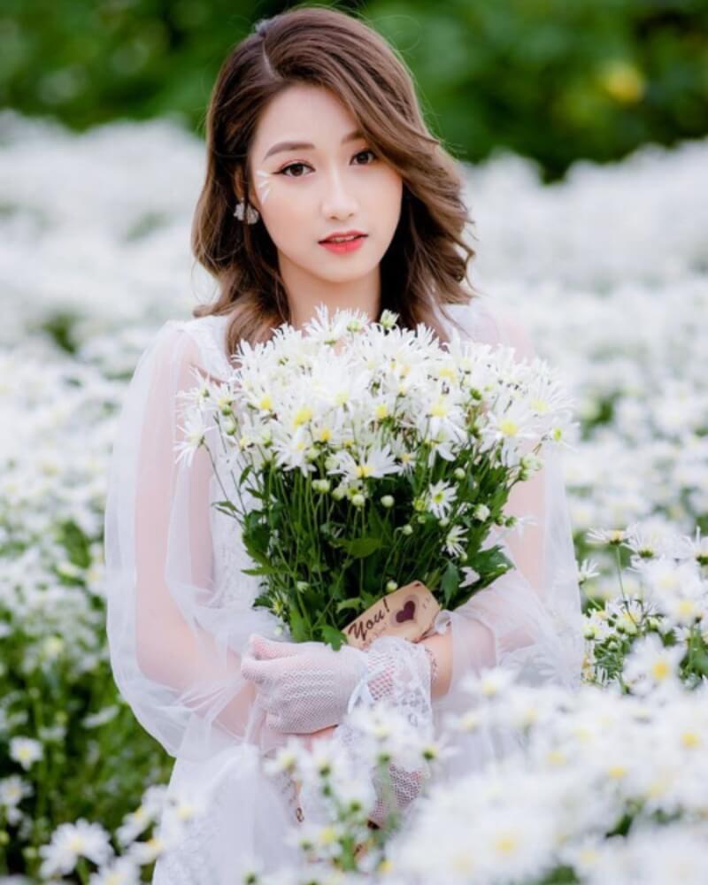 Ảnh gái xinh cute ở vườn hoa, tay cầm bó hoa cúc họa mi