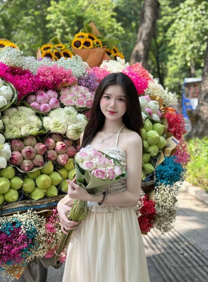 Ảnh gái xinh Việt Nam cầm hoa sen đứng trước xe bán hoa