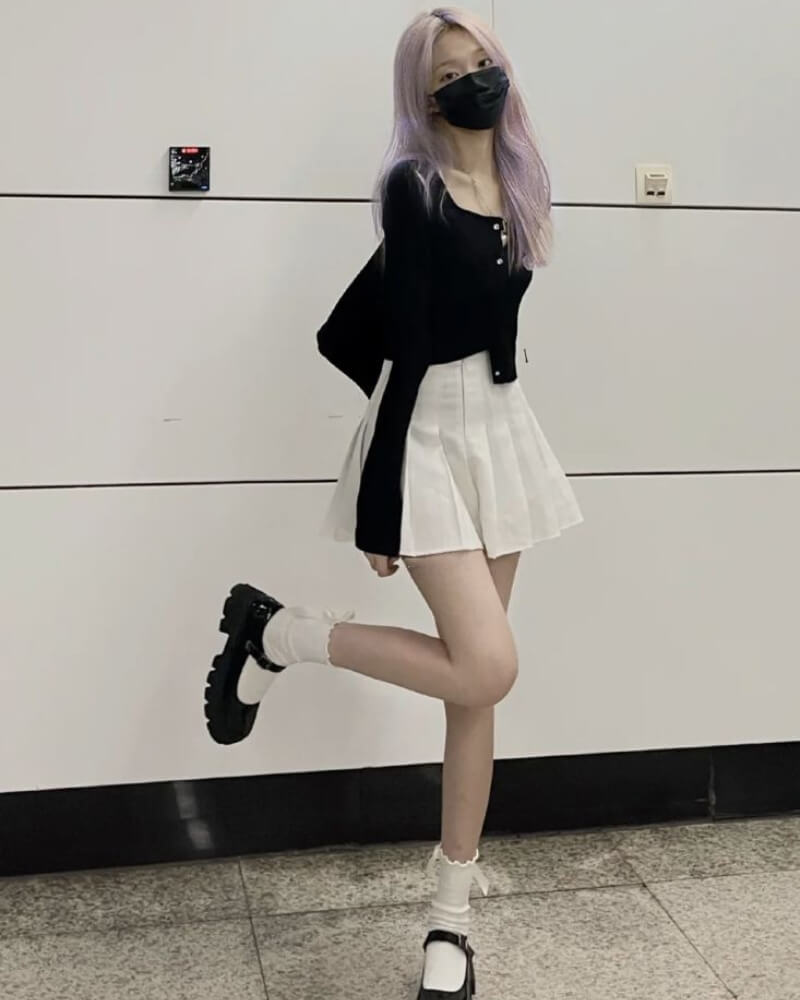 Gái xinh mặc váy ngắn xếp ly đứng trước bức tường