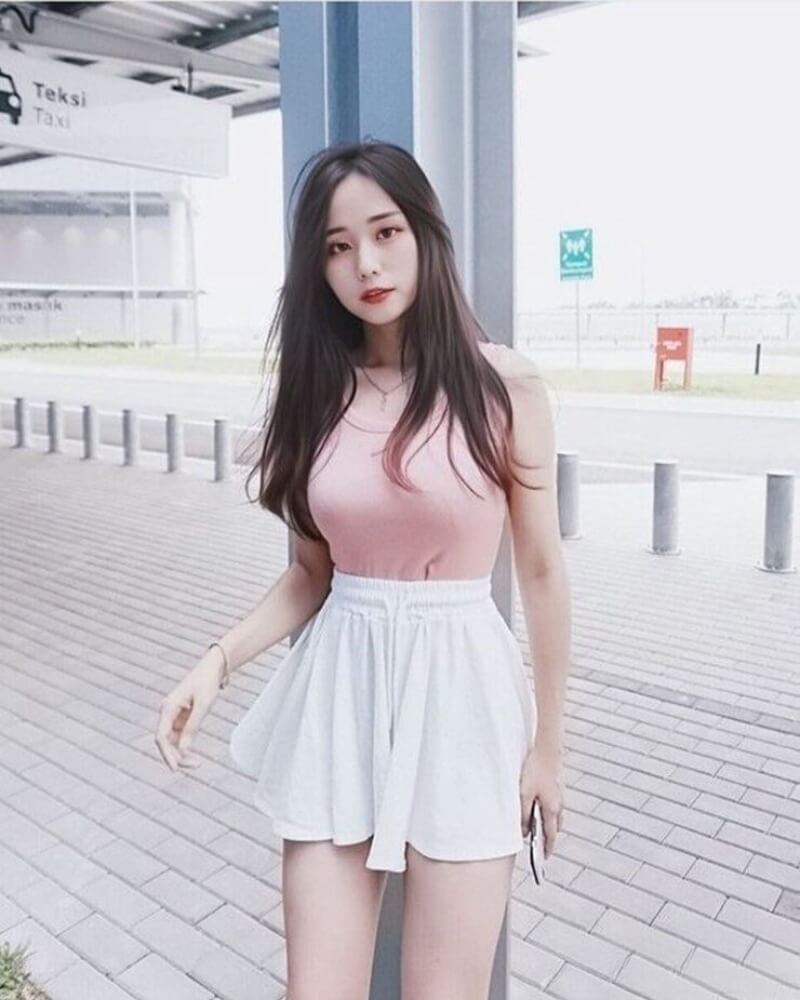 Ảnh gái xinh mặc váy ngắn trắng đứng tựa vào cột