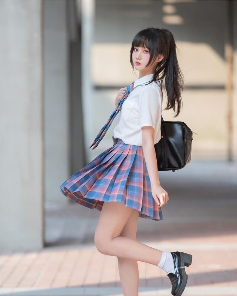 Gái xinh mặc váy ngắn xếp ly đeo balo đen