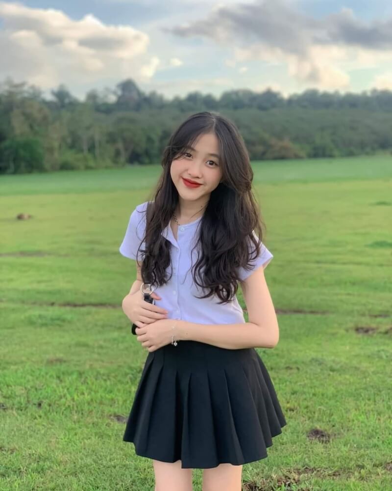 Gái xinh mặc váy ngắn xếp ly ở bãi cỏ xanh