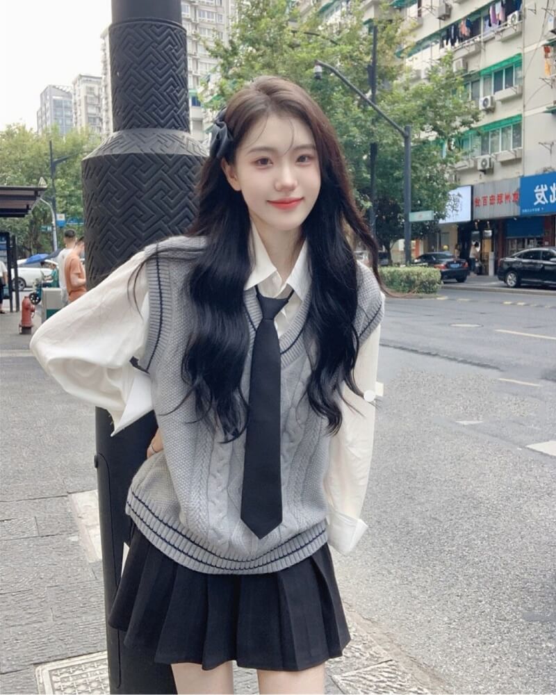 Gái xinh Trung Quốc mặc váy ngắn xếp ly đen tựa lưng vào cột trên phố