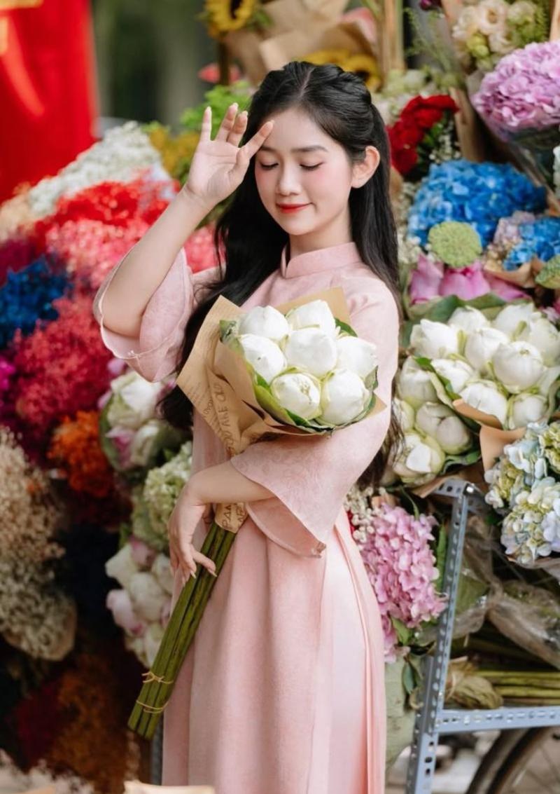 Gái xinh áo dài ôm bông sen trắng đứng trước xe bán hoa