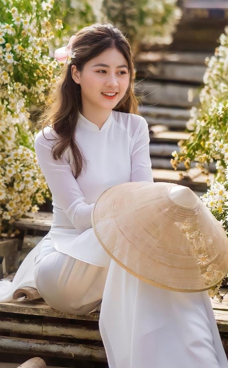 Gái xinh áo dài trắng ngồi ở cầu thang cầm nón lá