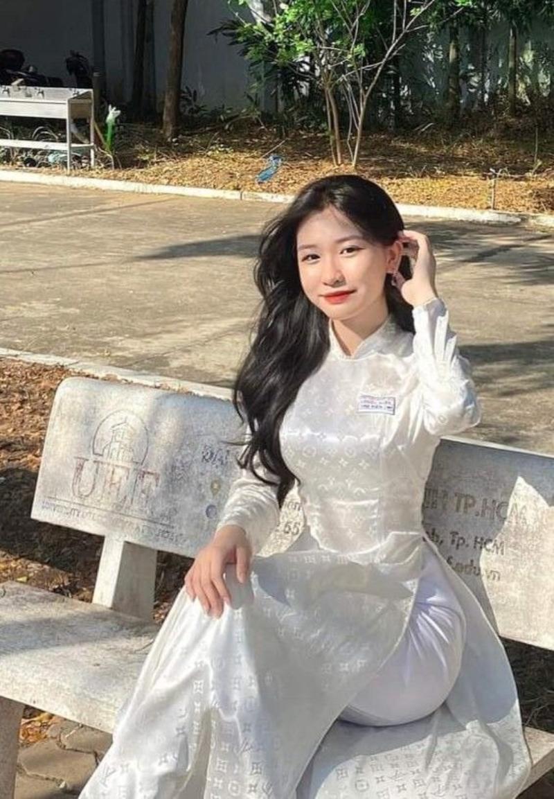 Gái xinh áo dài trắng ngồi trên ghế đá