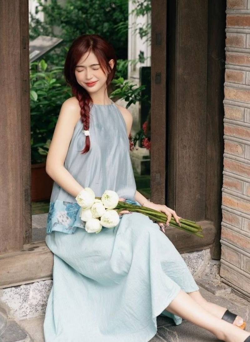 Gái xinh áo dài xanh cầm hoa ngồi ở khung cửa