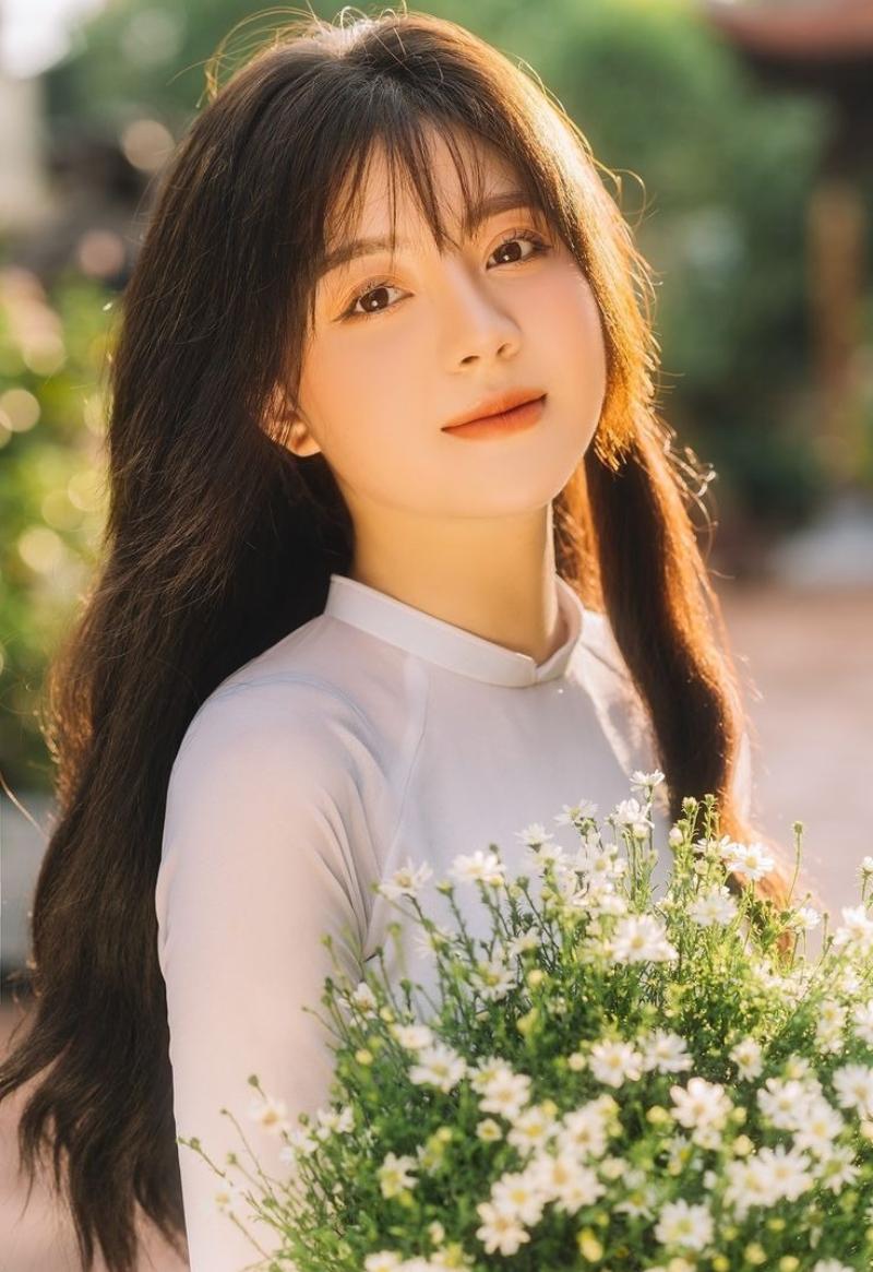 Gái xinh áo dài trắng tay ôm bó hoa cúc họa mi