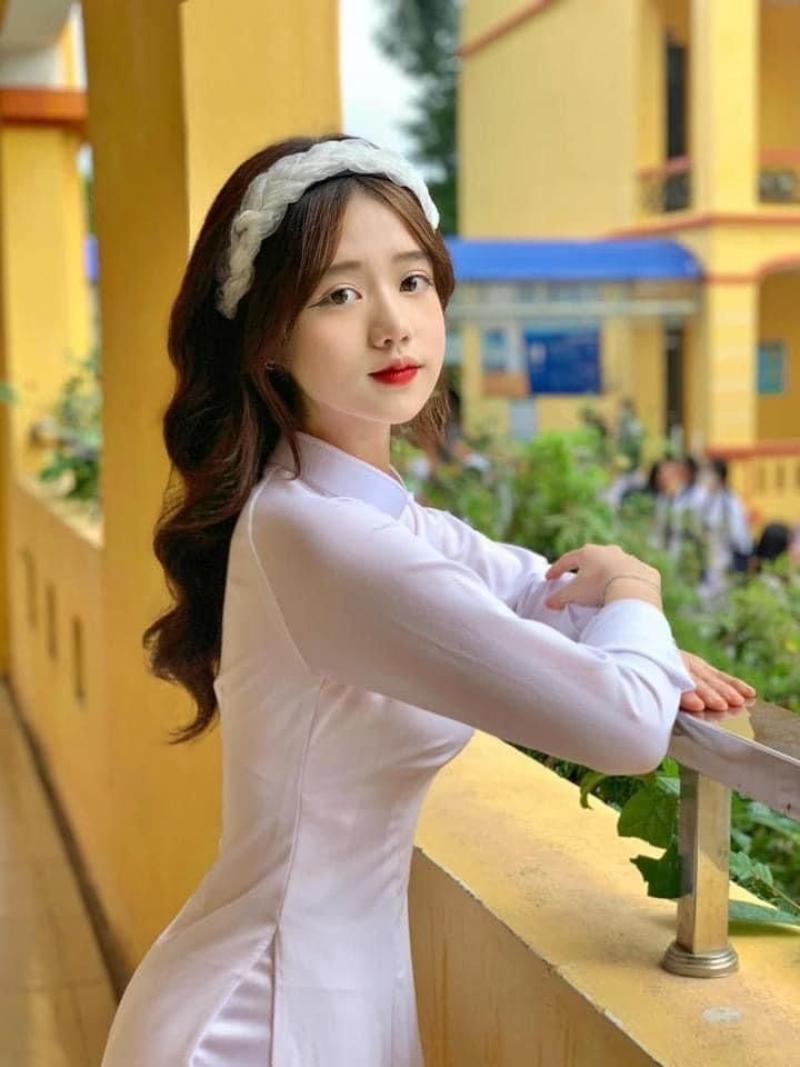 Gái xinh áo dài trắng đứng nghiêng người tựa tay vào lan can lớp học