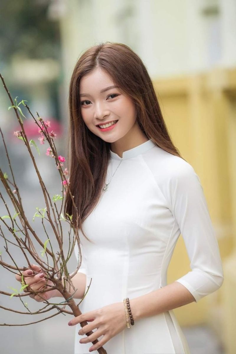 Gái xinh áo dài trắng cầm nhánh hao đào