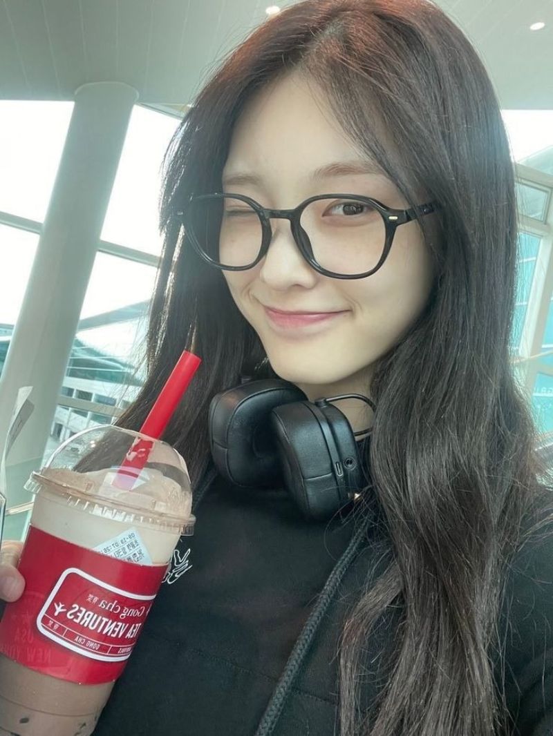Ảnh gái xinh tóc dài đeo kính tay cầm ly trà sữa