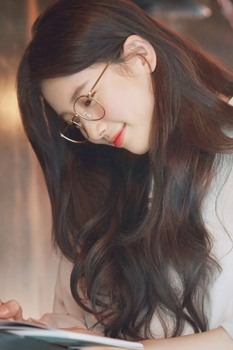 Ảnh gái xinh tóc dài đeo kính đọc sách cười nhẹ