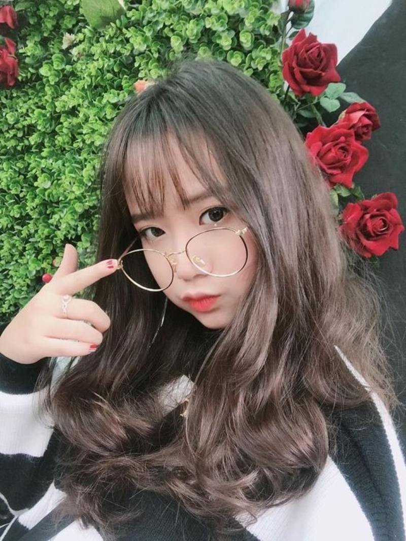 Ảnh gái xinh tóc dài đeo kính trước bụi hoa hồng