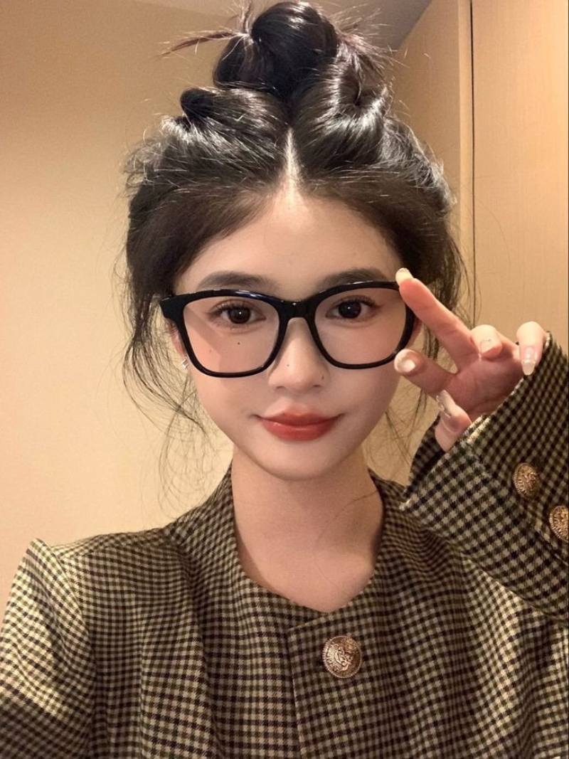 Ảnh gái xinh tóc dài đeo kính trước bức tường vàng cam