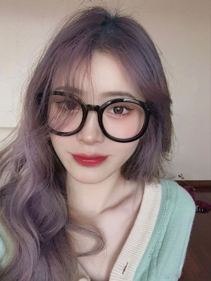Ảnh gái xinh tóc dài đeo kính trước bức tường trơn