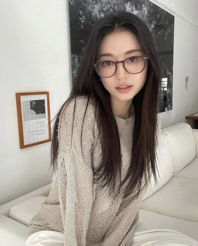 Ảnh gái xinh tóc dài đeo kính ngồi trên giường