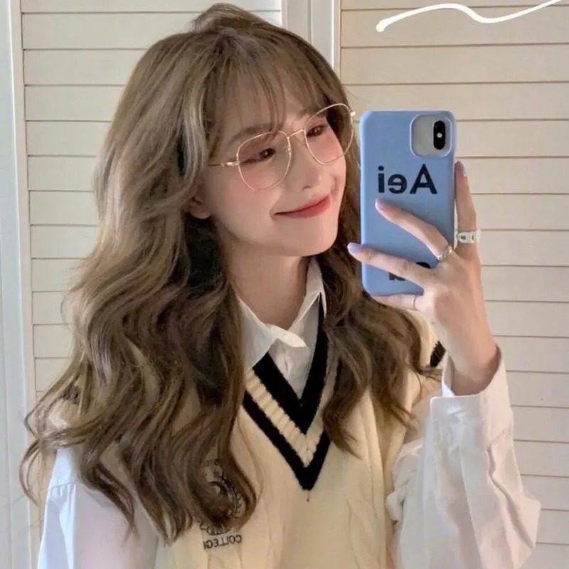 Ảnh gái xinh tóc dài đeo kính tay cầm điện thoại chụp ảnh cười nhẹ