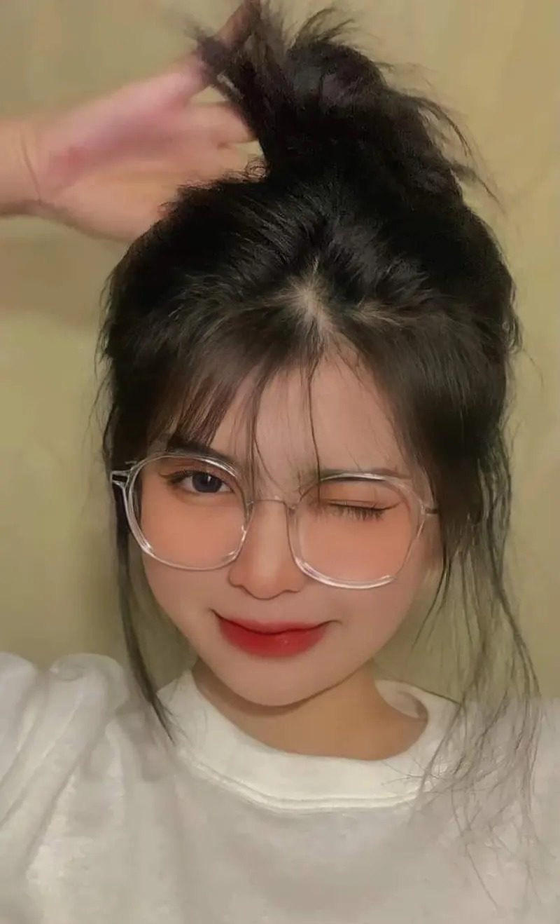 Ảnh gái xinh tóc dài đeo kính tay nâng tóc, nháy mắt trái