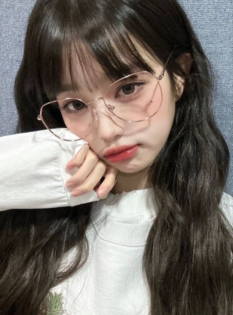 Ảnh gái xinh tóc dài đeo kính tay phải chạm vào má
