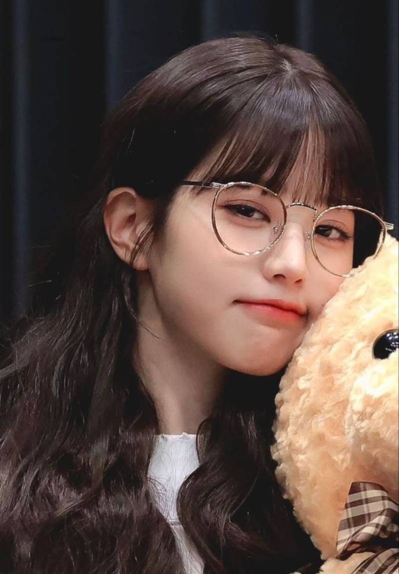 Ảnh gái xinh tóc dài đeo kính tựa mặt vào gấu bông