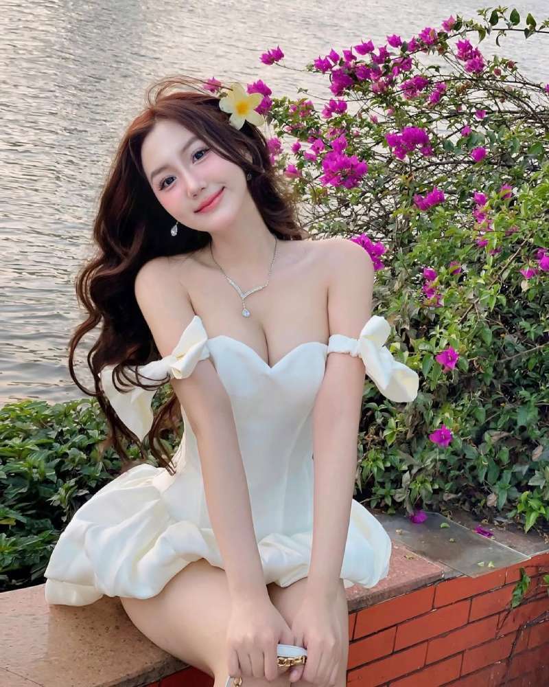 Gái xinh mặc đồ hở hang với bộ váy trắng bên cạnh cây hoa giấy