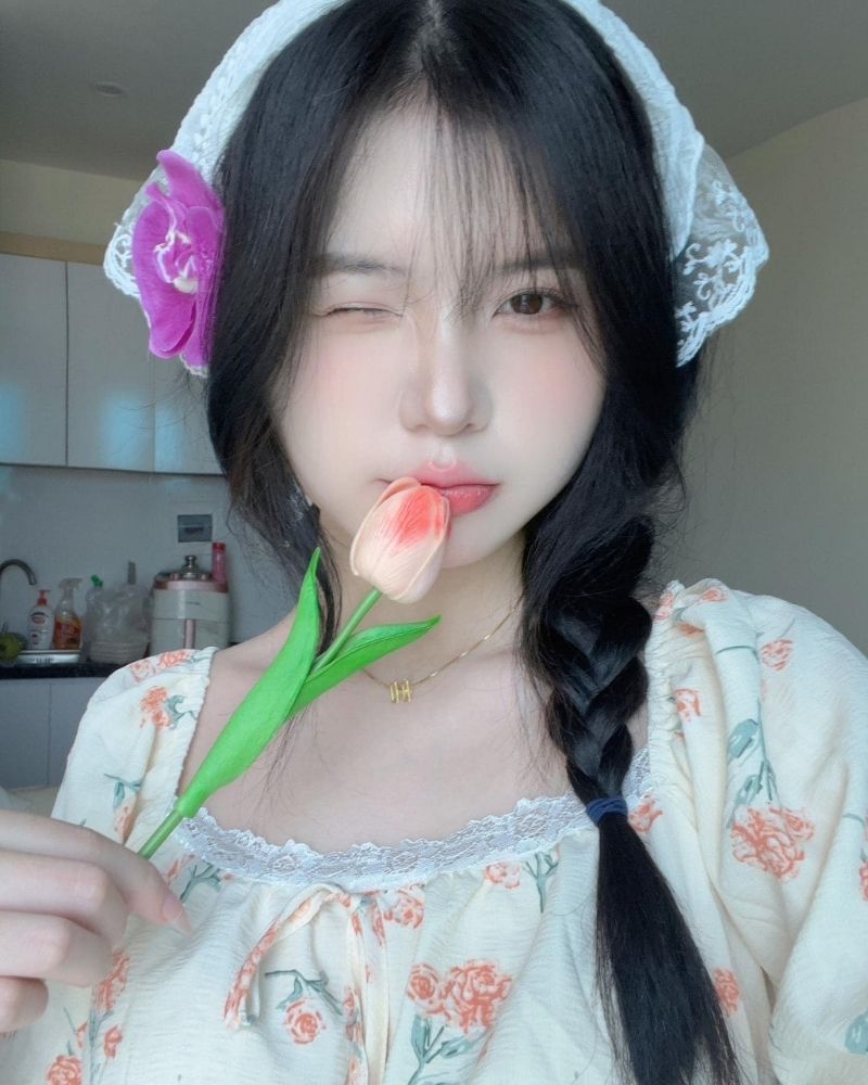 Ảnh gái xinh tự sướng nheo mắt phải tay cầm hoa