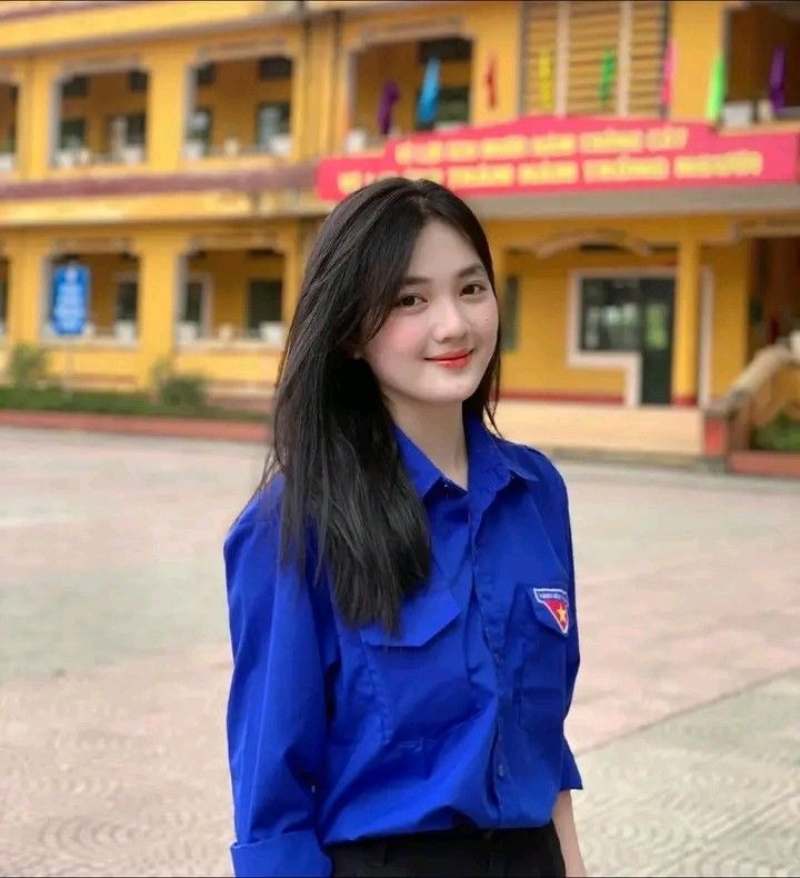Gái học sinh mặc áo đoàn viên đứng dưới sân trường Gái học sinh mặc áo đoàn viên đứng dưới sân trường