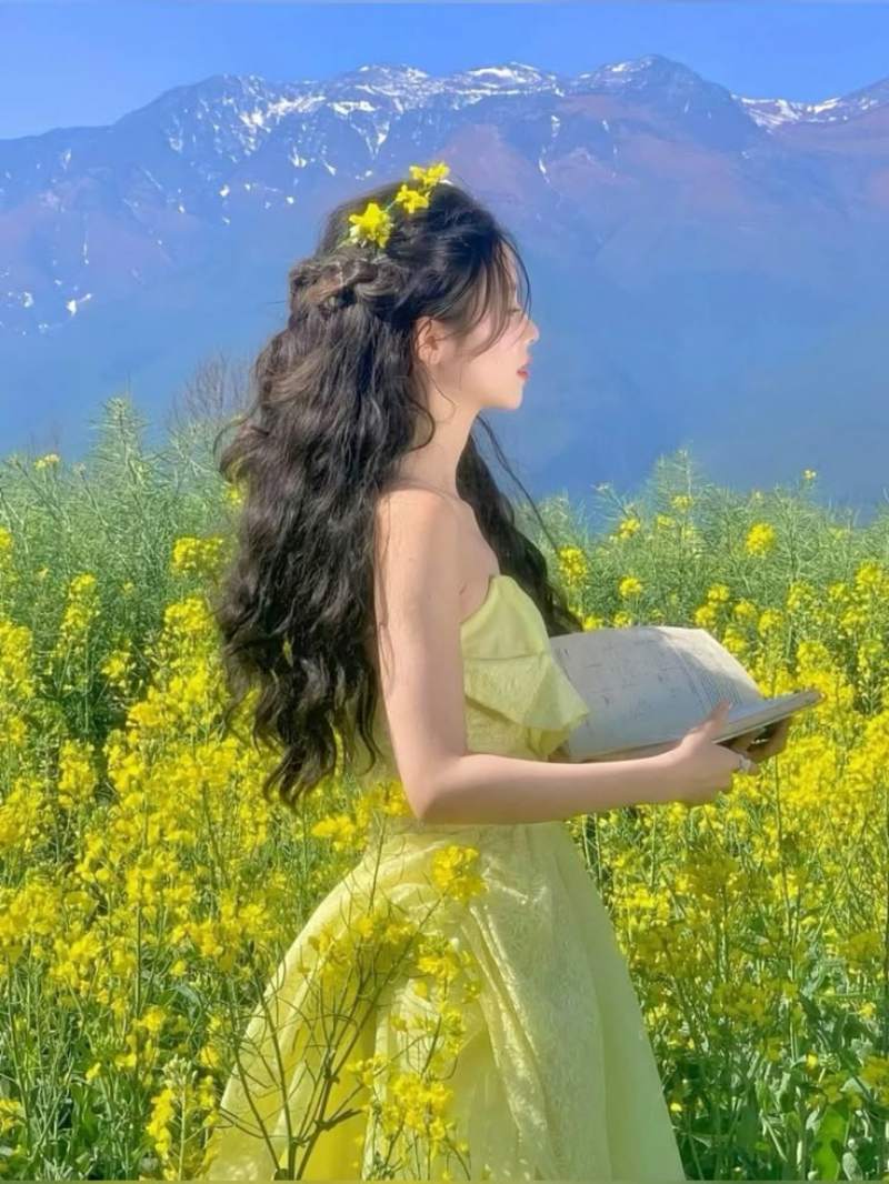 Ảnh gái xinh Trung Quốc mặc váy vàng cầm sách ở vườn hoa