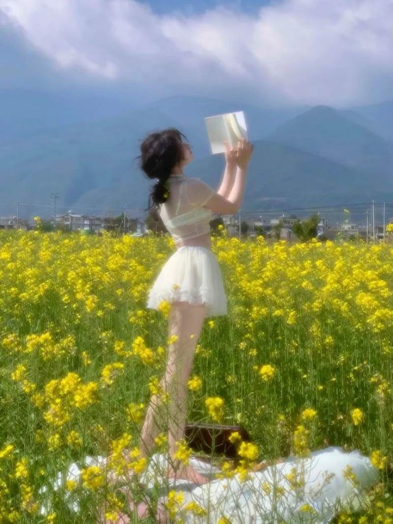 Ảnh gái xinh Trung Quốc mặc váy ngắn trắng cầm sách đọc ở vườn hoa