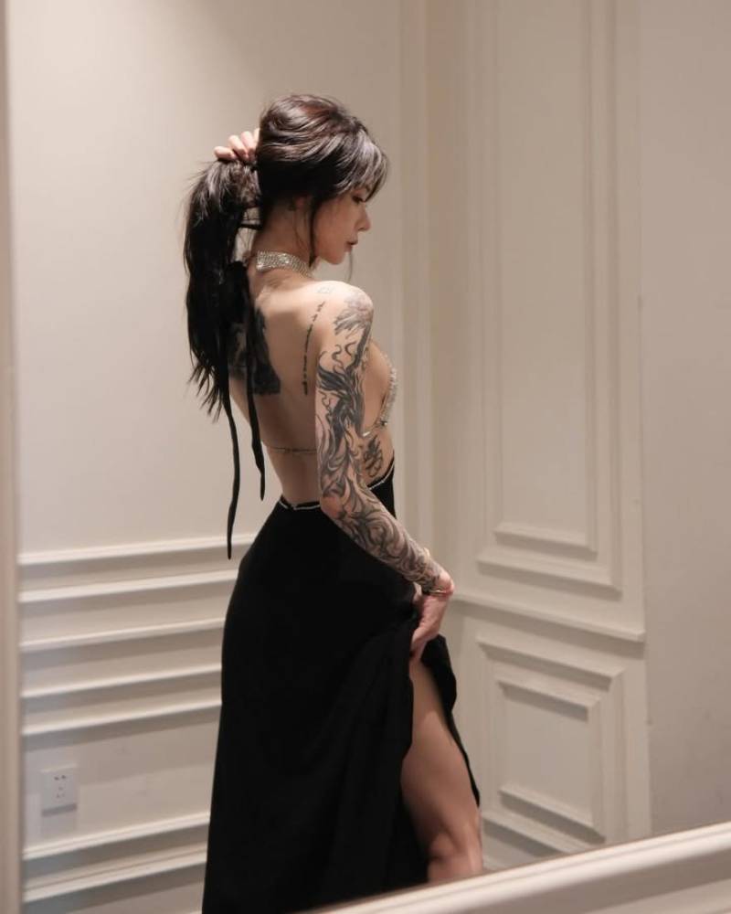 Gái xăm hình kín tay mặc váy đen đứng quay người khoe lưng